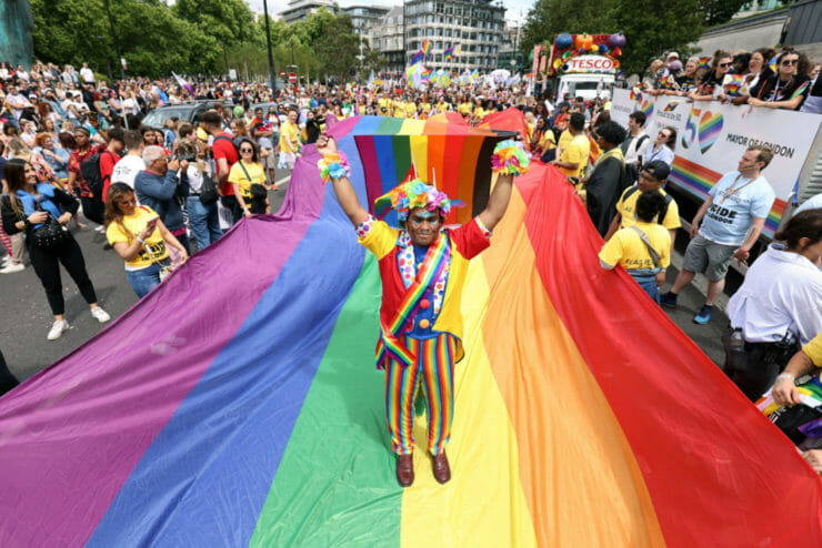 Mohammed Nazir z Londýna pózuje na veľkej dúhovej vlajke pred začiatkom londýnskeho pochodu Pride pri príležitosti 50. výročia hnutia Pride v Británii v Londýne 2. júla 2022.