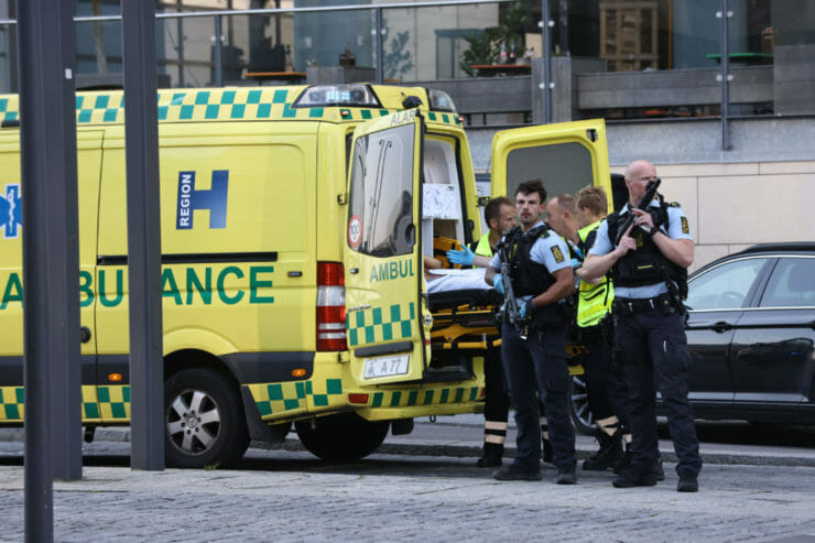 Záchranári a policajti stoja neďaleko nákupného centra, v ktorom došlo ku streľbe v dánskom meste Orestad 3. júla 2022.