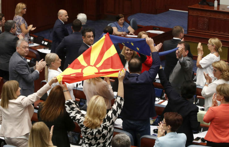 Poslanci vládnej koalície tlieskajú a mávajú vlajkami EÚ a Severného Macedónska po hlasovaní v parlamente 16. júla 2022 v Skopje.
