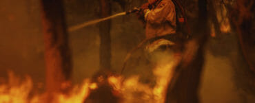 Hasič bojuje s plameňmi počas lesného požiaru