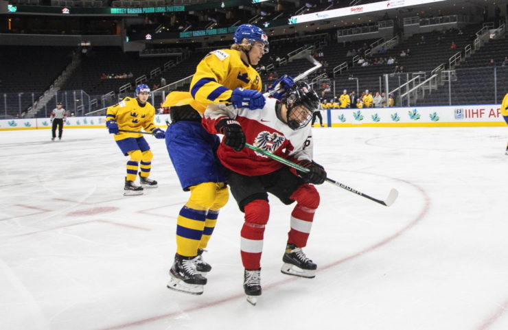 Švédsky hokejista Simon Edvinsson (7) a Ian Scherzer (26) z Rakúska počas zápasu B-skupiny Rakúsko - Švédsko na majstrovstvách sveta hráčov do 20 rokov v Edmontone 12. augusta 2022.