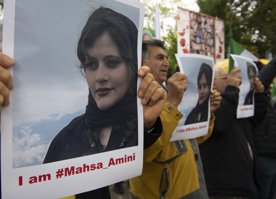 Ľudia držía fotografiu zosnulej mladej Iránky Mahsá Amíníovej počas protestu pred iránskym veľvyslanectvom v Berlíne.