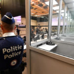 Policajt stojí pri presklenných kabínkach pre obvinených v súdnej sieni pred začiatkom úvodného vypočutia s obvinenými v kauze teroristických útokov z roku 2016 v Justičnom paláci v Bruseli 12. septembra 2022.