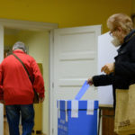 volička vhadzuje obálku s hlasovacími lístkami do volebnej schránky pre voľby do VÚC