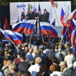 Ľudia sledujú na veľkoplošnej obrazovke ako ruský prezident Vladimir Putin pózuje s lídrami okupovaných oblastí po podpise zmluvy o pričlenení štyroch oblastí Ukrajiny k Rusku v Kremli v Moskve, v meste Sevastopoľ na Kryme 30. septembra 2022. Foto: tasr/ap