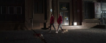 Ľudia kráčajú so psami po tmavej ulici v meste Záporožie na juhovýchode Ukrajiny v stredu 19. októbra 2022.