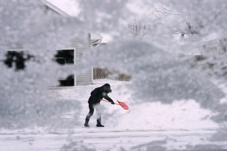 Miestny obyvateľ odhrabáva sneh z príjazdovej cesty v meste Urbandale, americkom štáte Iowa vo štvrtok 22. decembra 2022.