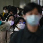 Na archívnej snímke z 20. decembra 2022 cestujúci v ochranných rúškach kráčajú na stanici metra počas rannej špičky v Pekingu.