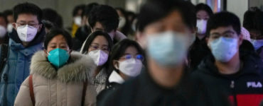 Na archívnej snímke z 20. decembra 2022 cestujúci v ochranných rúškach kráčajú na stanici metra počas rannej špičky v Pekingu.