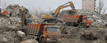 Robotníci odstraňujú ruiny budovy divadla v Mariupole 24. decembra 2022.