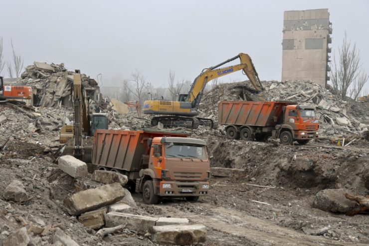 Robotníci odstraňujú ruiny budovy divadla v Mariupole 24. decembra 2022.